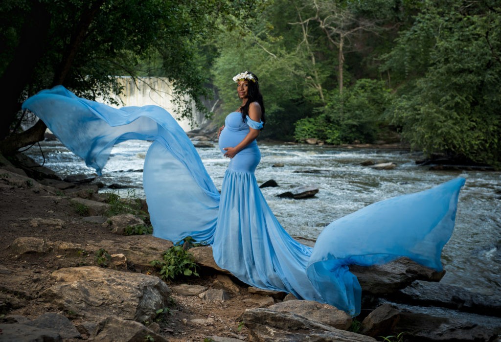 girl with long flowy blue dress standing near river