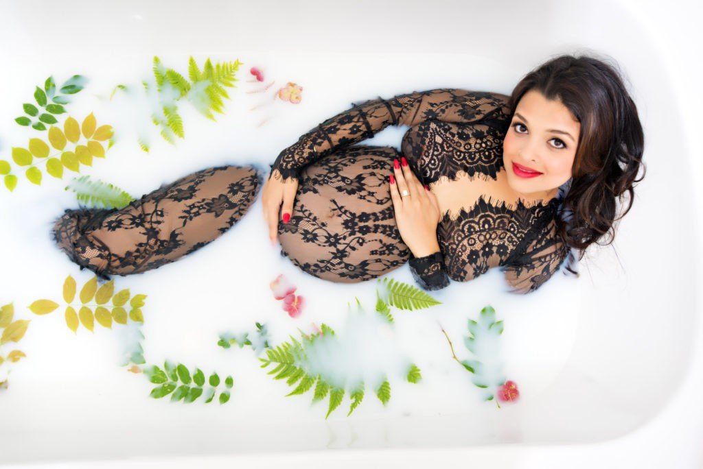 high angle photograph of pregnant girl laying in bathtub holding stomach